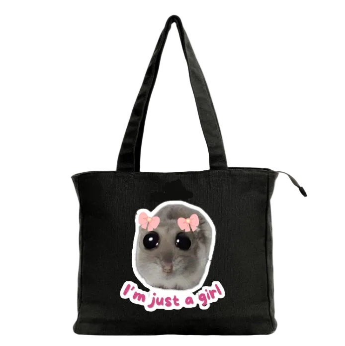 Black tote bag with a graphic of a small animal wearing pink bows and text 'I'm just a girl' on a white background.